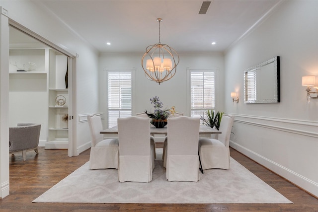 dining space featuring a chandelier, wood finished floors, visible vents, and crown molding