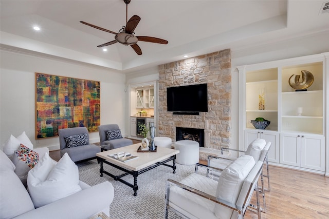 living area with light wood-style floors, a tray ceiling, visible vents, and a fireplace