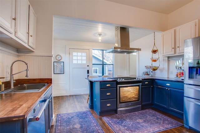 kitchen with blue cabinets, a sink, stainless steel appliances, white cabinets, and island range hood