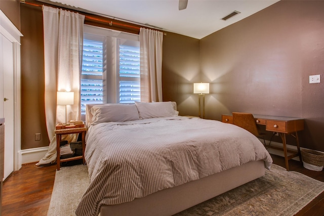 bedroom featuring a ceiling fan, wood finished floors, visible vents, and baseboards