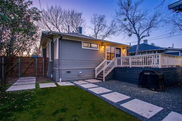 view of front of property featuring a front lawn, fence, a wooden deck, a chimney, and a gate