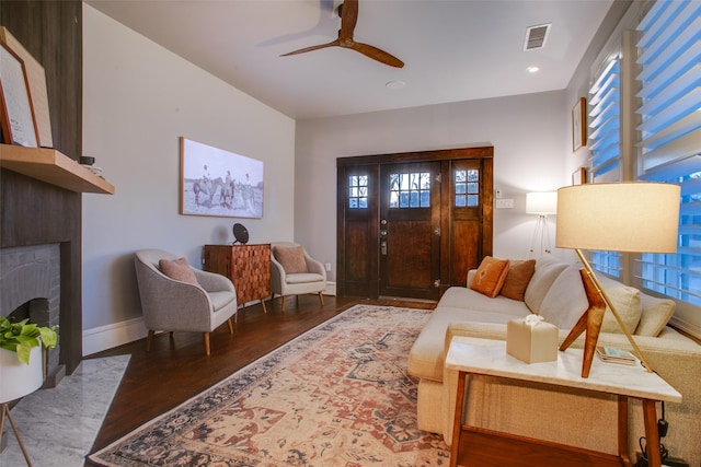 living area featuring visible vents, wood finished floors, a fireplace, baseboards, and ceiling fan