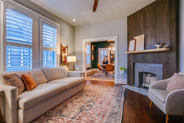 living room with a fireplace, recessed lighting, wood finished floors, and baseboards