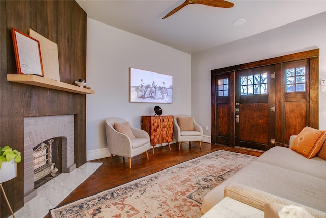 entryway with ceiling fan, baseboards, wood finished floors, and a fireplace