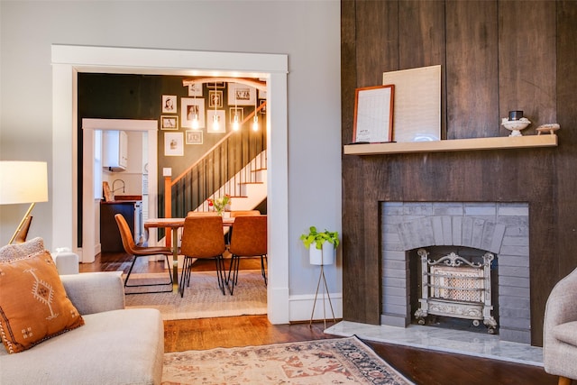 living area featuring stairway, baseboards, wood finished floors, and a fireplace