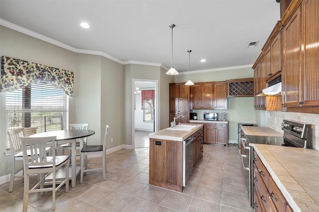 2118 Darby Dan Ct, Granbury, TX 76049 - kitchen featuring appliances with stainless steel finishes, tile countertops, brown cabinets, crown molding, and a sink
