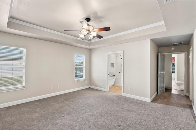 unfurnished bedroom featuring visible vents, ornamental molding, a tray ceiling, carpet, and baseboards