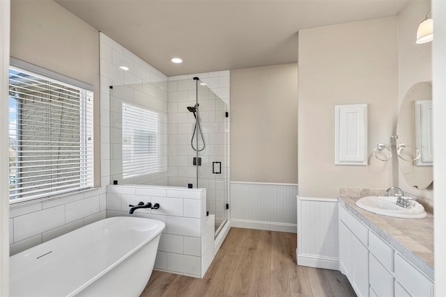 bathroom with a wainscoted wall, wood finished floors, a healthy amount of sunlight, and a stall shower