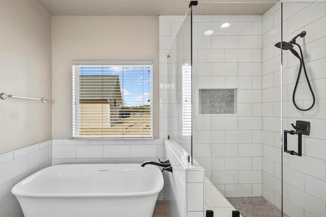 bathroom with a freestanding tub, tile walls, and a shower stall