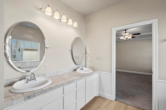 full bath with double vanity, wood finished floors, wainscoting, and a sink