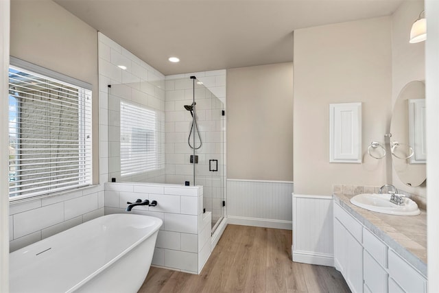 2118 Darby Dan Ct, Granbury, TX 76049 - full bath featuring wood finished floors, a shower stall, a soaking tub, a wainscoted wall, and vanity