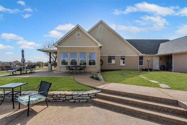 rear view of property featuring a patio area, a lawn, and brick siding