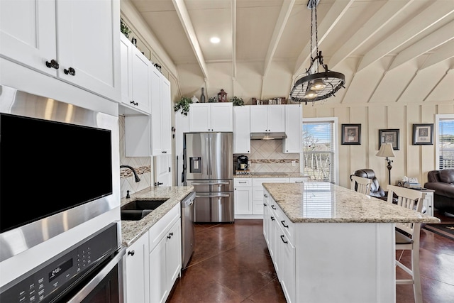 kitchen featuring backsplash, beamed ceiling, a breakfast bar, stainless steel appliances, and a sink