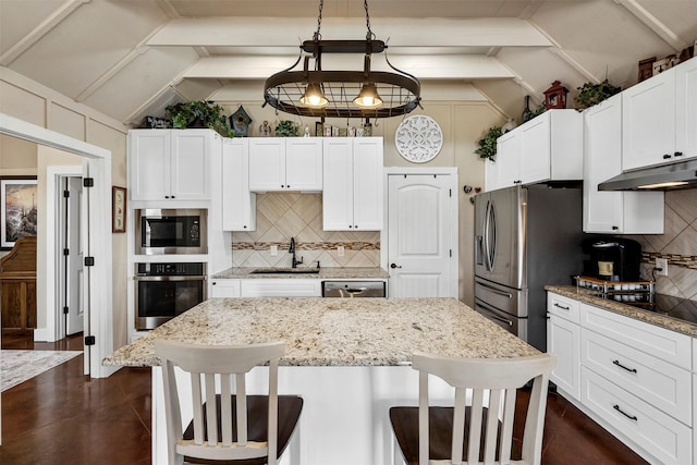 kitchen with a sink, lofted ceiling, a kitchen breakfast bar, and stainless steel appliances