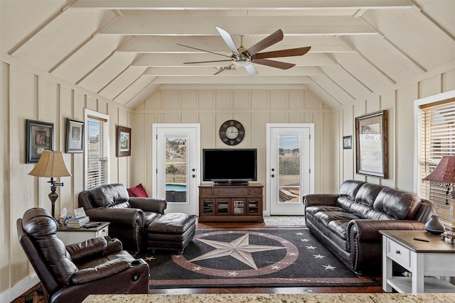 living area featuring a decorative wall, a ceiling fan, and lofted ceiling