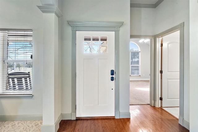 entryway with decorative columns, baseboards, and wood finished floors