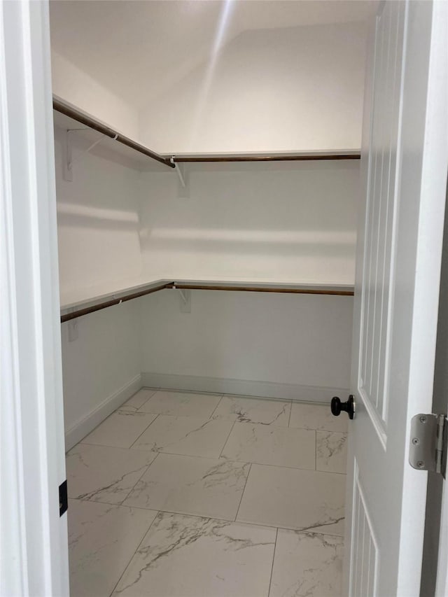 walk in closet featuring marble finish floor