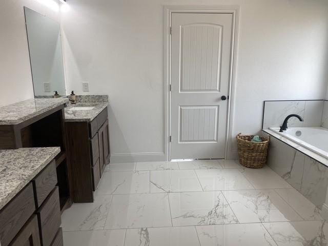 bathroom featuring marble finish floor, baseboards, a garden tub, and vanity