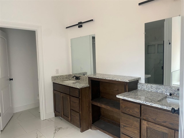 full bathroom featuring marble finish floor, baseboards, two vanities, and a sink