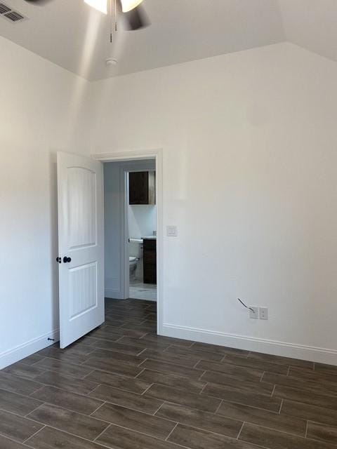 empty room featuring wood tiled floor, visible vents, vaulted ceiling, and baseboards