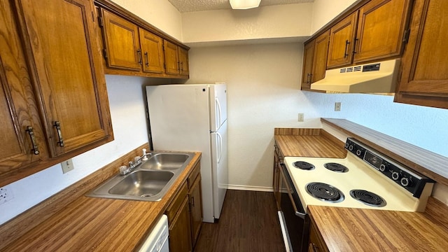 kitchen with white appliances, brown cabinetry, wood counters, under cabinet range hood, and a sink