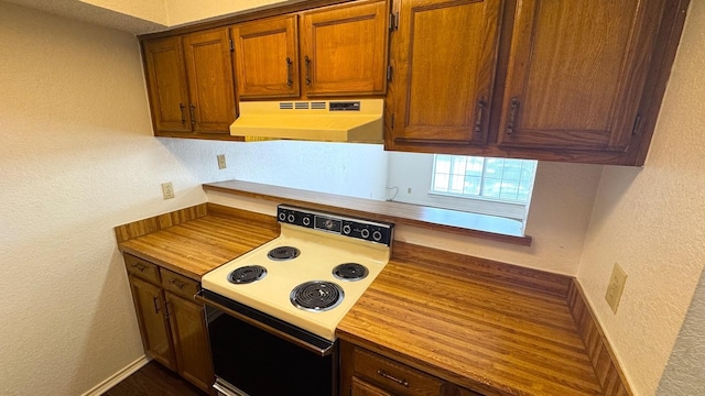 kitchen with range with electric cooktop, a textured wall, and under cabinet range hood