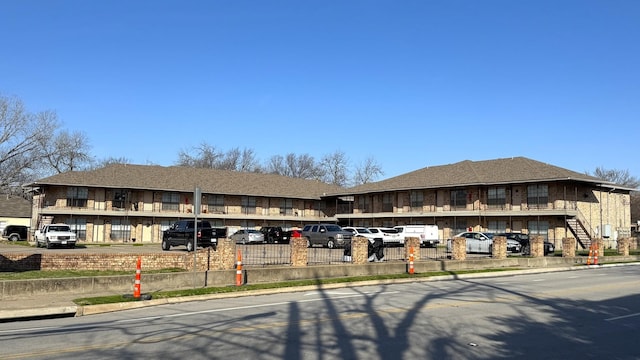 view of building exterior featuring uncovered parking and fence