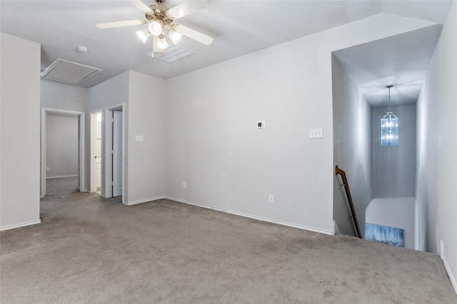 carpeted spare room featuring attic access and a ceiling fan