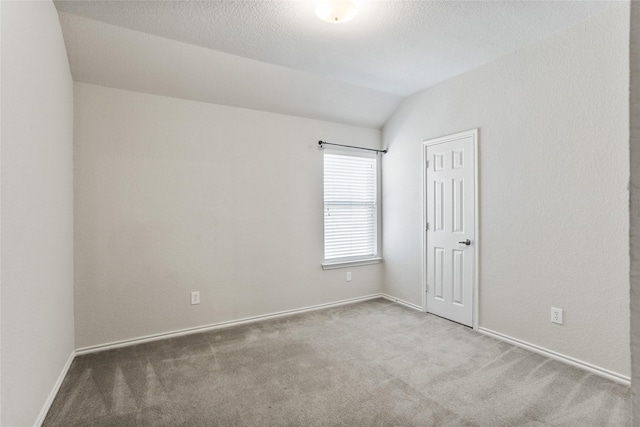 empty room featuring baseboards, a textured ceiling, carpet, and vaulted ceiling