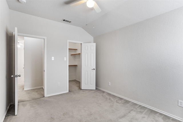 unfurnished bedroom with a ceiling fan, visible vents, vaulted ceiling, a spacious closet, and carpet flooring