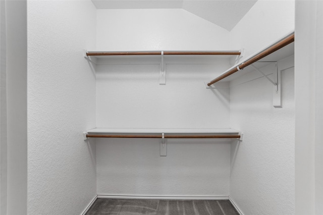 spacious closet featuring lofted ceiling and dark carpet