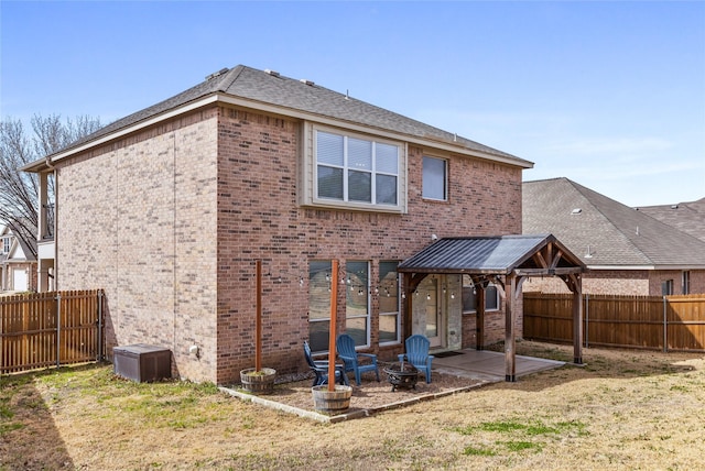 rear view of house featuring brick siding, a fire pit, a gazebo, a fenced backyard, and a patio area