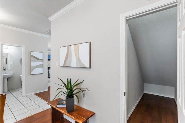 hall with tile patterned floors, baseboards, ornamental molding, and a sink