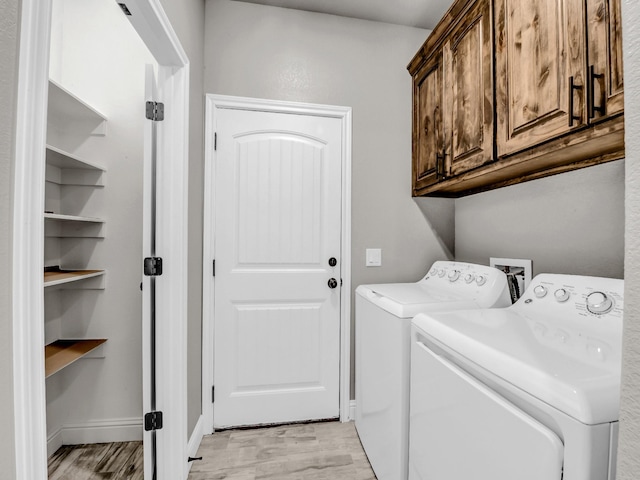 laundry area featuring separate washer and dryer, light wood-style flooring, cabinet space, and baseboards