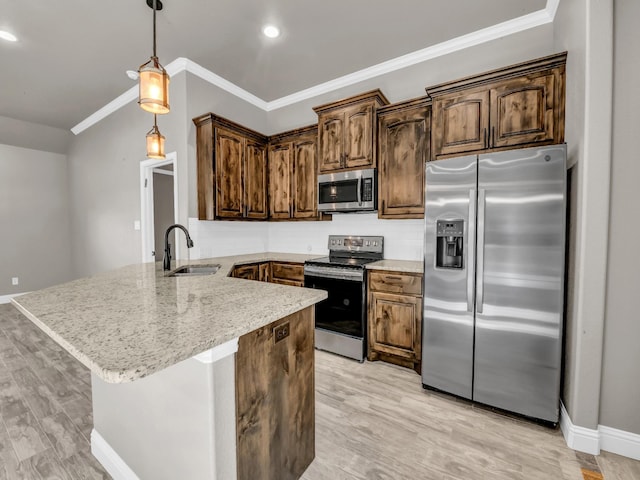 kitchen featuring a peninsula, a sink, hanging light fixtures, ornamental molding, and appliances with stainless steel finishes