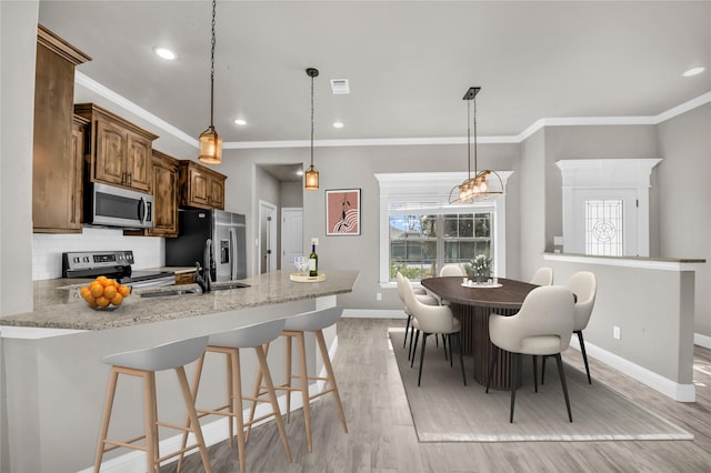 kitchen with light wood-style flooring, stainless steel appliances, a peninsula, baseboards, and backsplash