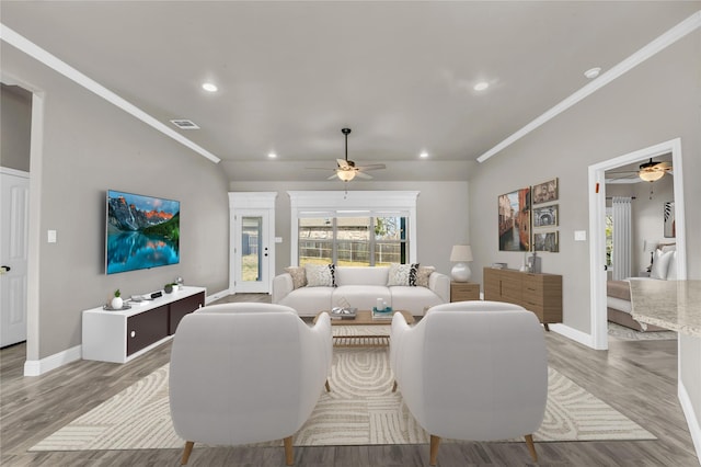 living area with ornamental molding, light wood-style floors, and baseboards