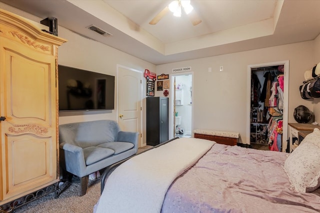 bedroom with ceiling fan, visible vents, a raised ceiling, and carpet flooring