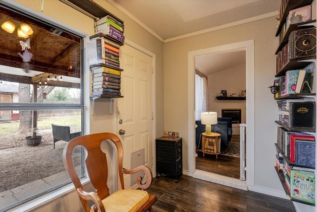 sitting room featuring baseboards, a fireplace, ornamental molding, and dark wood finished floors