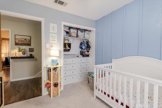 bedroom featuring a closet, visible vents, a crib, and baseboards