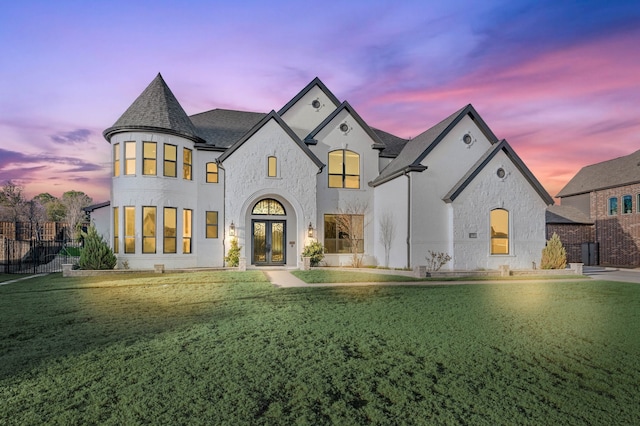 french country style house with a yard, french doors, a shingled roof, and fence