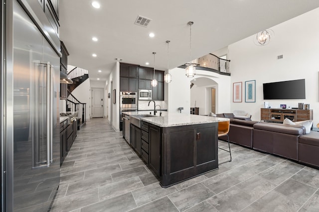 kitchen featuring arched walkways, stainless steel appliances, a sink, visible vents, and open floor plan