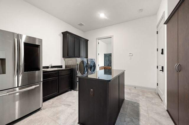 kitchen with visible vents, a center island, washing machine and clothes dryer, stainless steel refrigerator with ice dispenser, and a sink