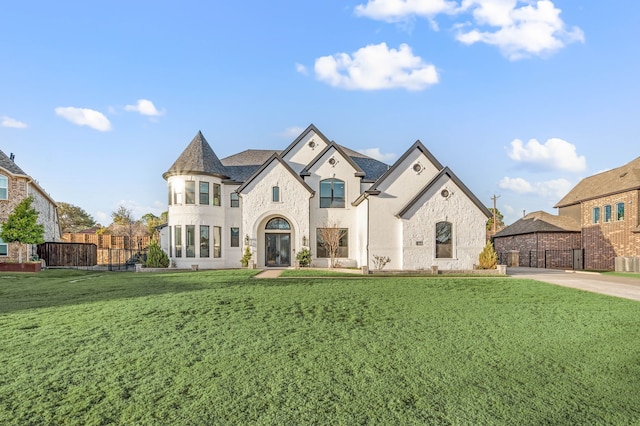 french provincial home featuring stone siding, fence, and a front yard