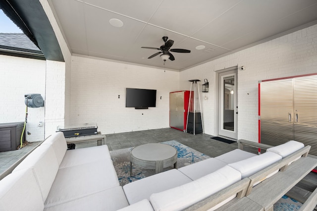 living area featuring brick wall and ceiling fan