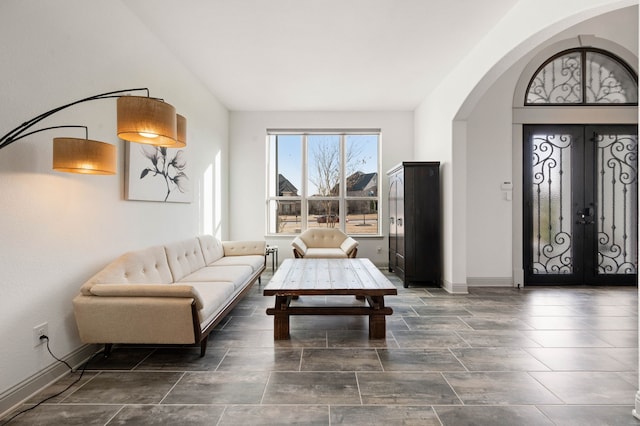 living room featuring arched walkways, french doors, and baseboards