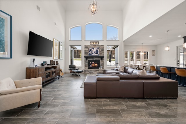 living room featuring recessed lighting, a notable chandelier, a fireplace, a towering ceiling, and visible vents