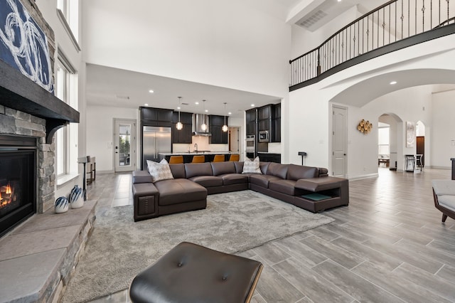 living area featuring a stone fireplace, plenty of natural light, visible vents, and baseboards