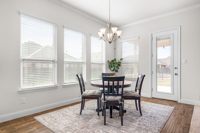 dining area with ornamental molding, a notable chandelier, baseboards, and wood finished floors