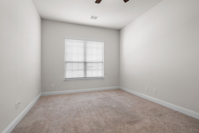 empty room featuring a ceiling fan, light colored carpet, and baseboards